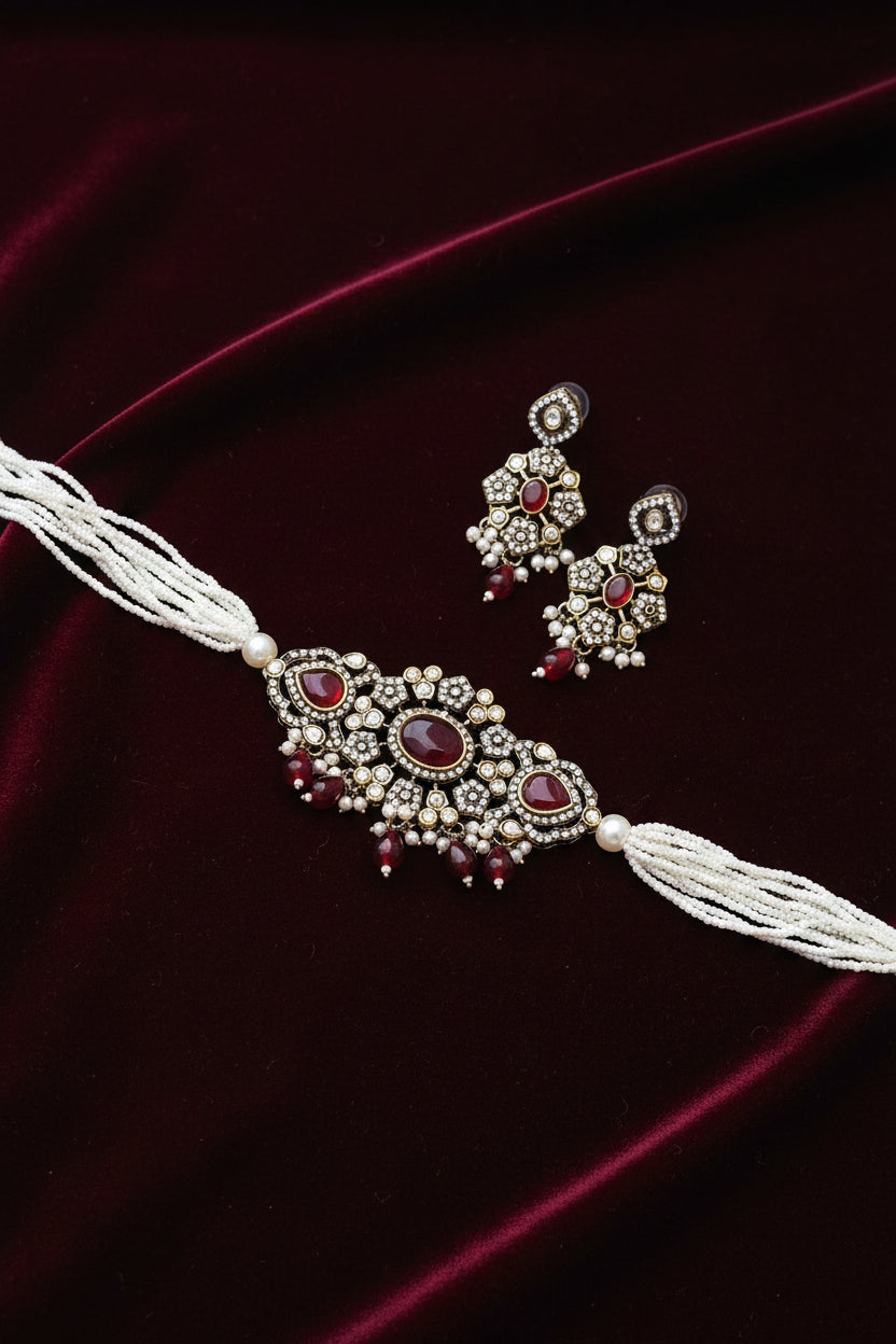 Ornate necklace and earrings on a red surface with a wooden box in the background