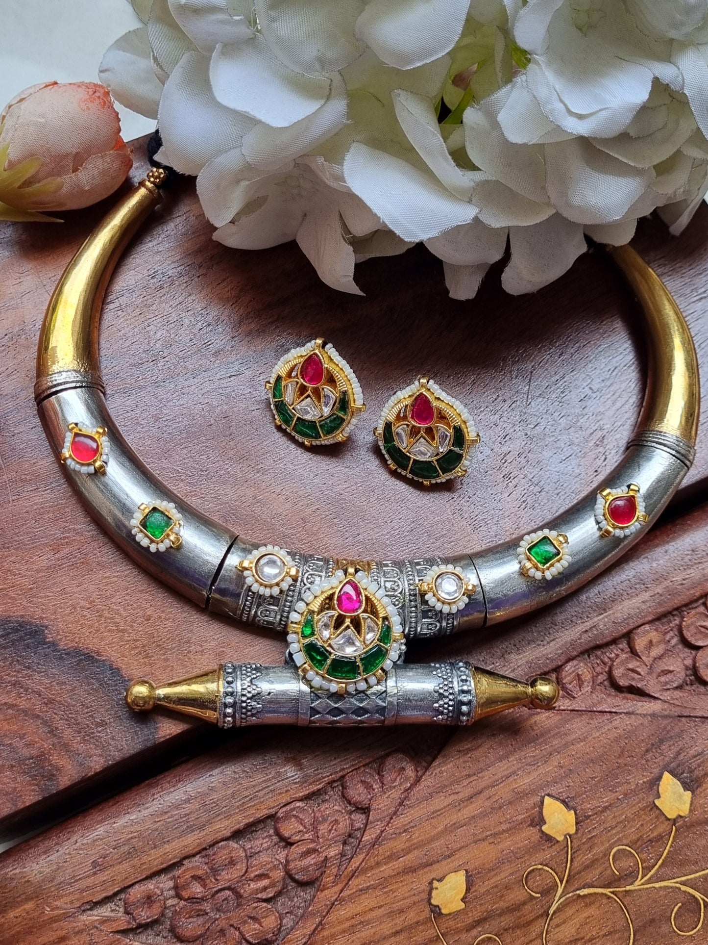 Silver necklace with red and green gemstones on a black background
