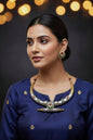 Ornate necklace and earrings on a dark fabric background with blurred lights