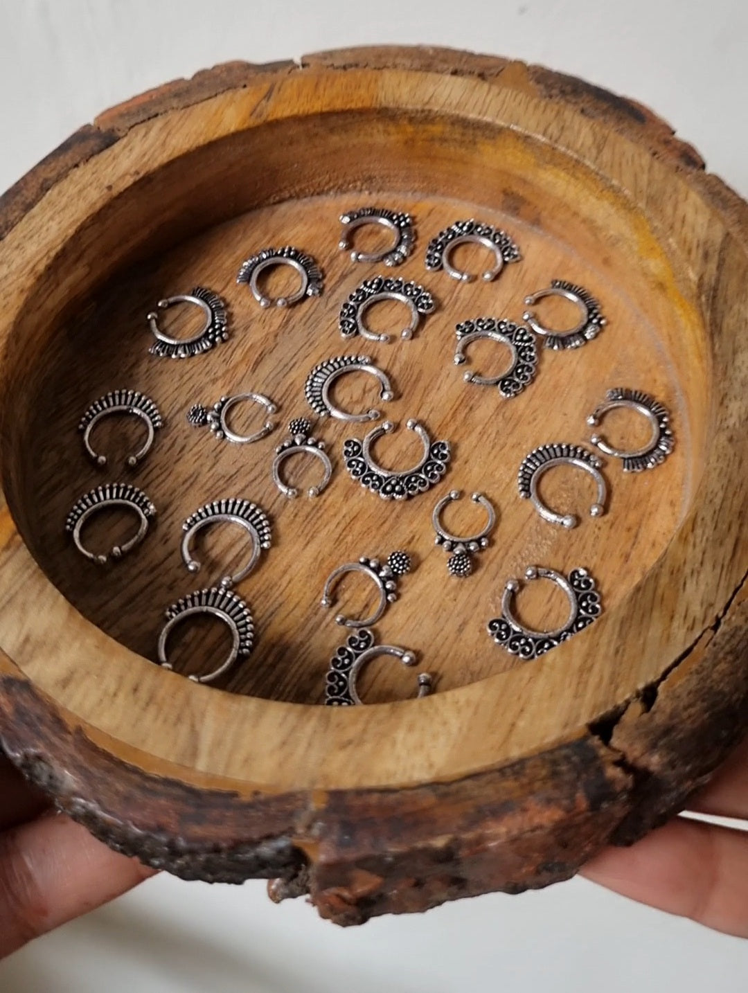 Collection of silver hoop earrings on a wooden tray